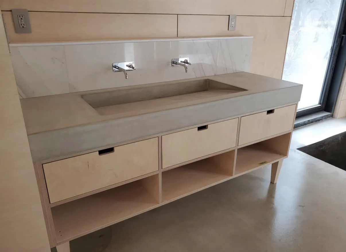A long integrated bathroom basin above light wood drawers and open storage