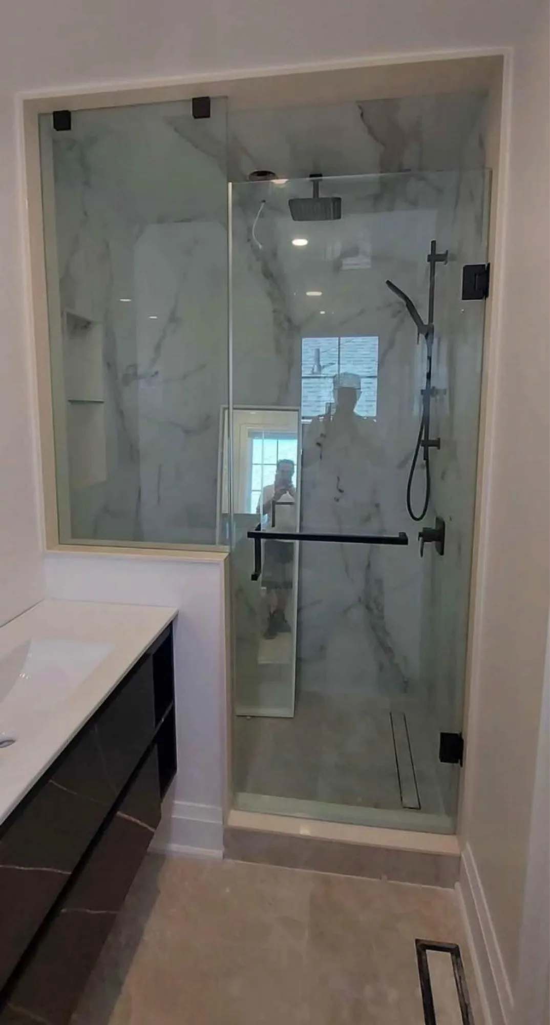 Carrara marble walk-in shower with matte black fixtures, frameless glass door, rain head and handheld combo — D&D Interior Services Waterloo