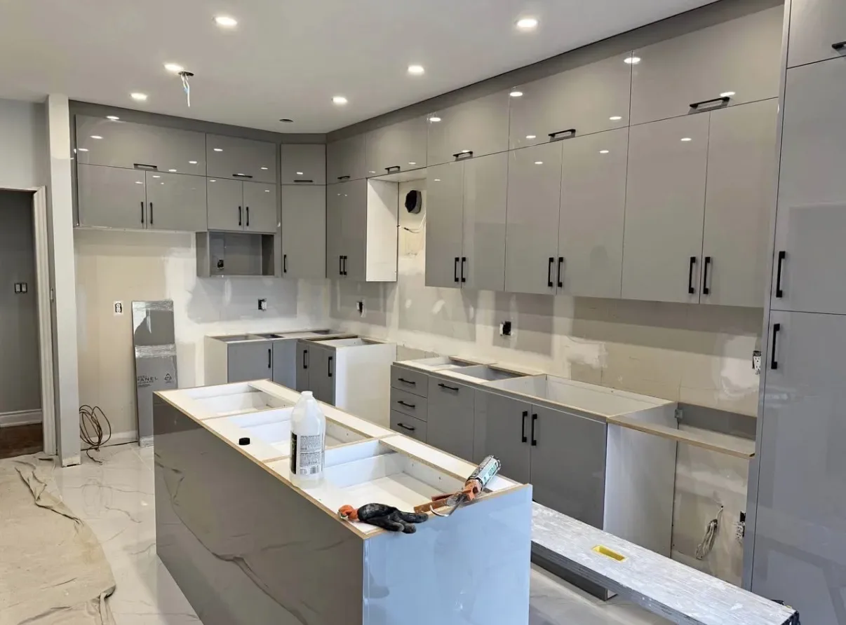 Kitchen interior during work, with grey cabinetry, recessed lights and tools on the island